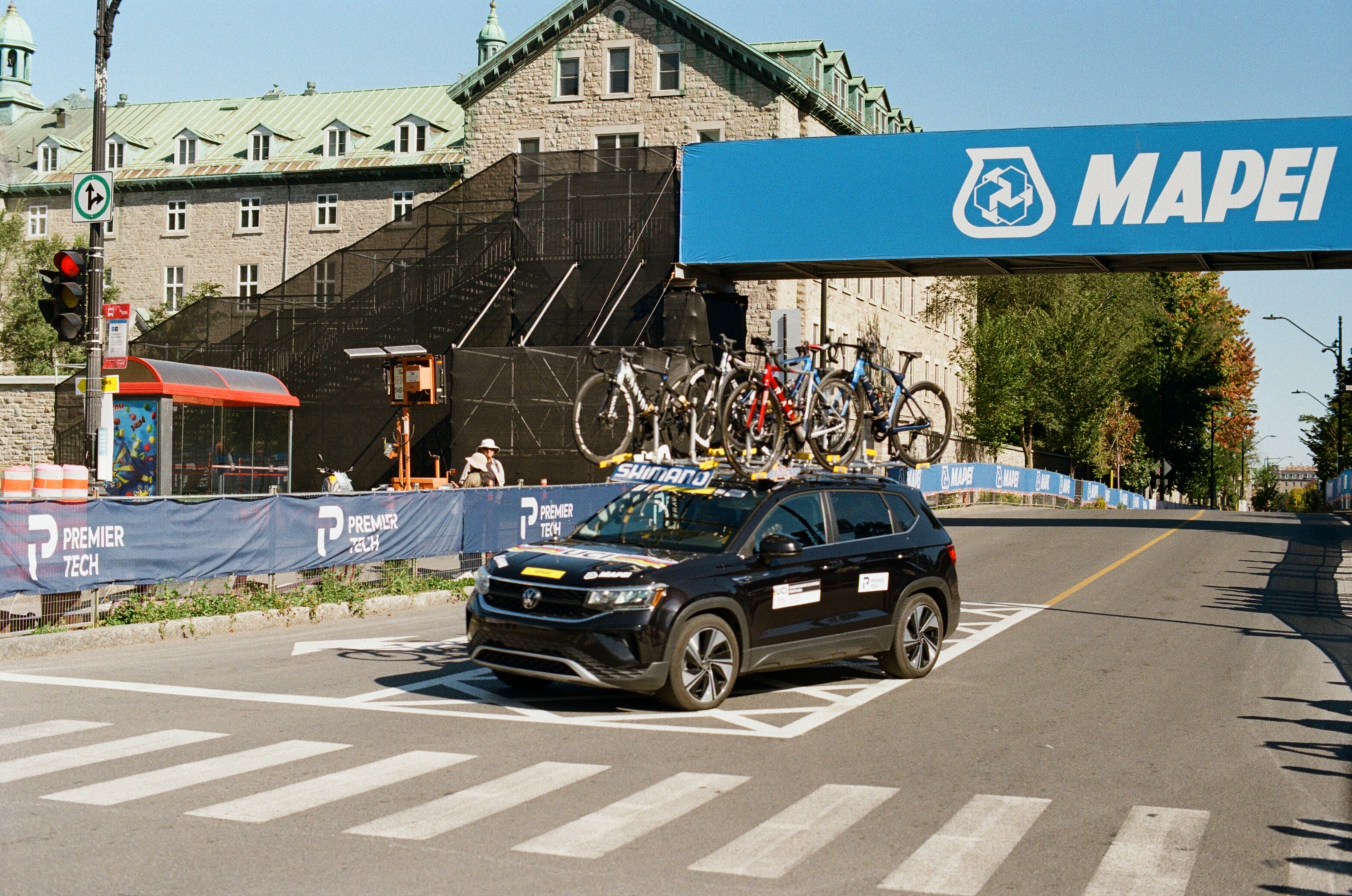 A car carrying bicycles rounds a corner in a women's bike race
