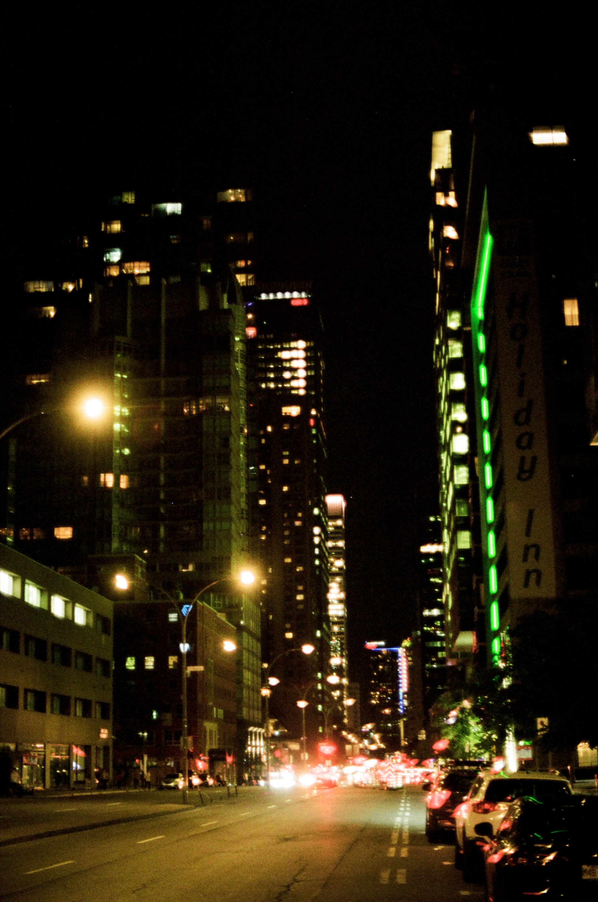 A city street surrounded by tall buildings at night