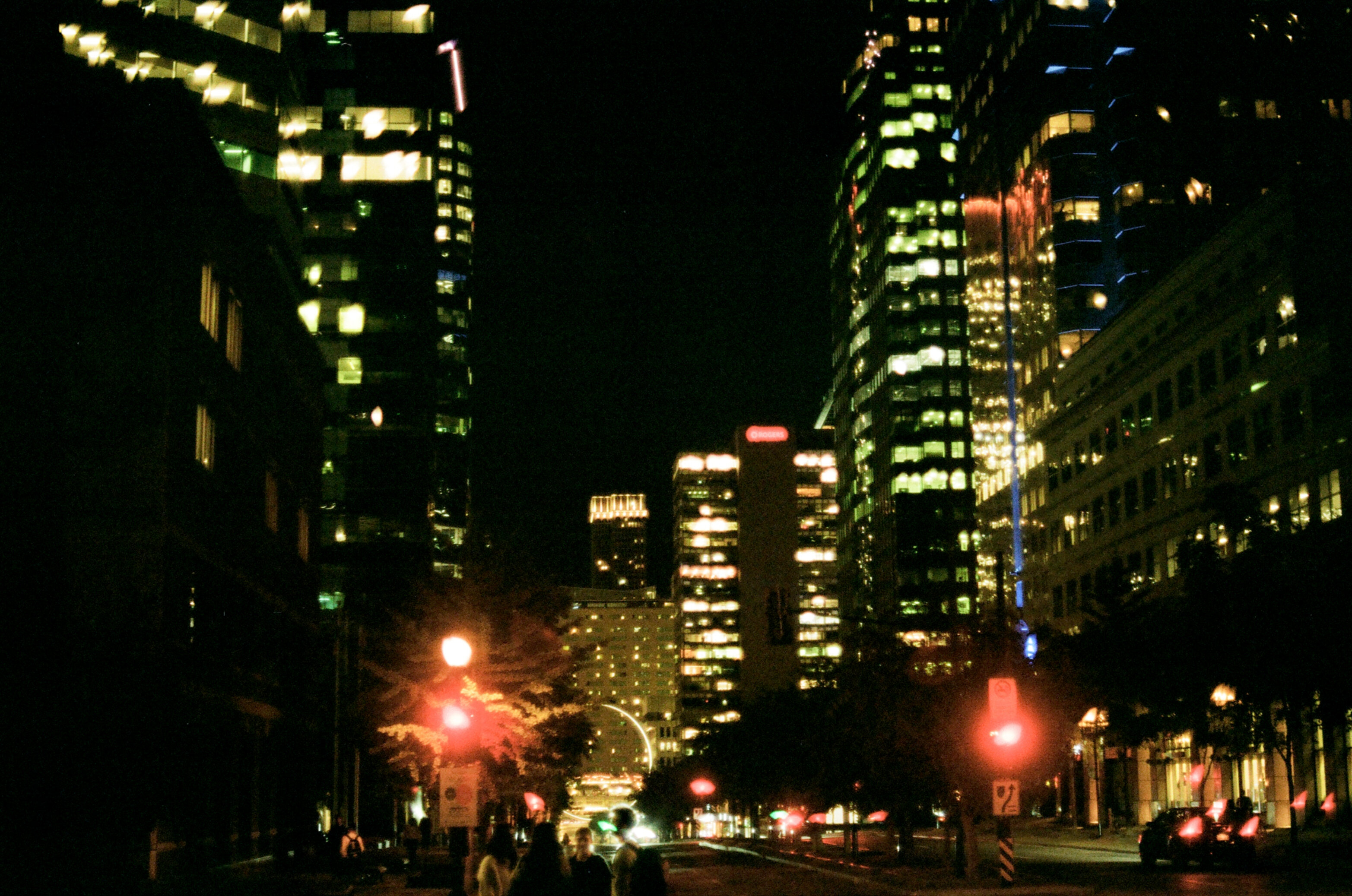 A city street surrounded by tall buildings at night