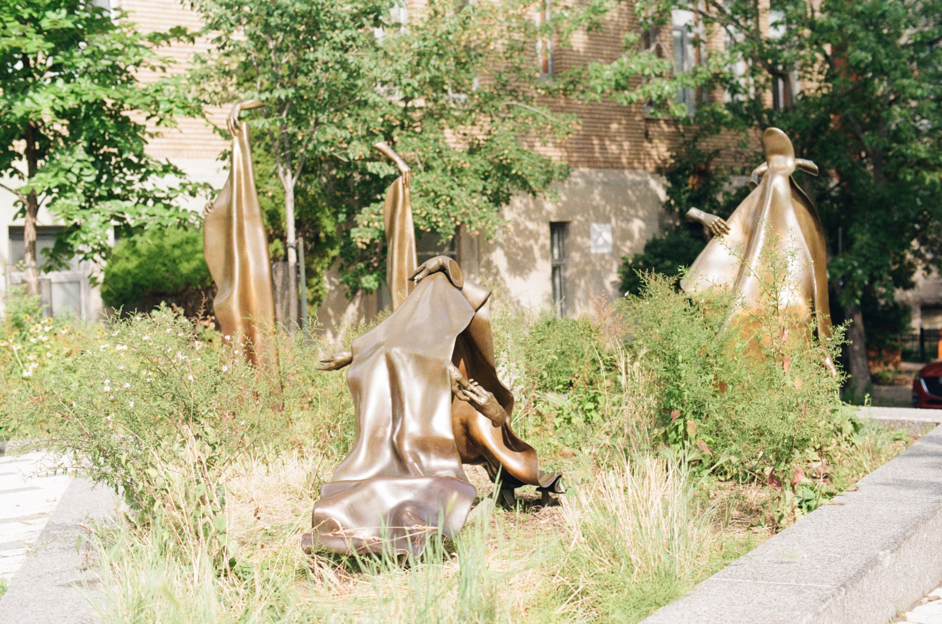 Bronze sculptures of that look wrinkled fabric and disembodied hands shining in the sunlight in a small park