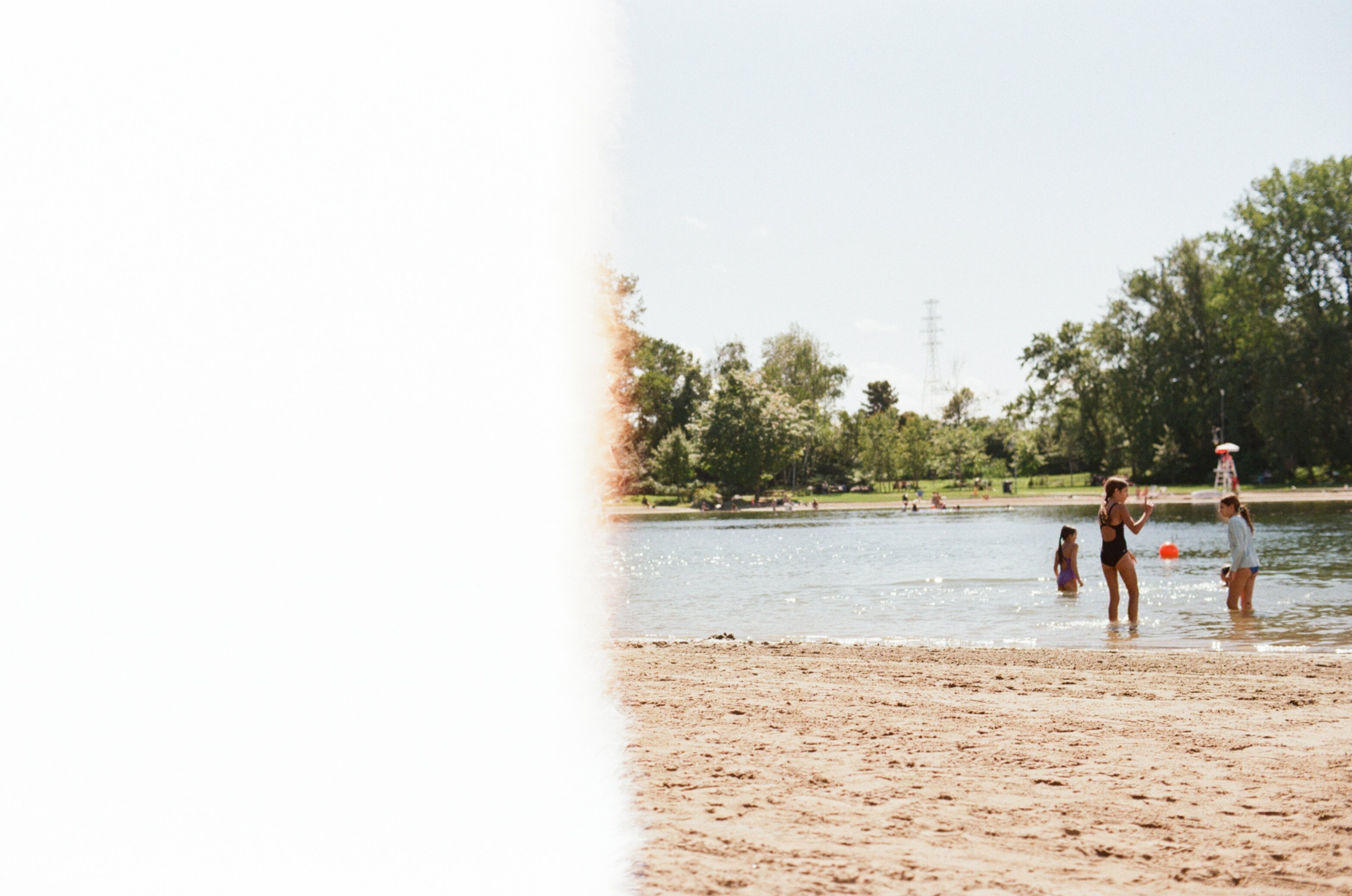 Kids play in the water at the beach but half the image is completely washed out