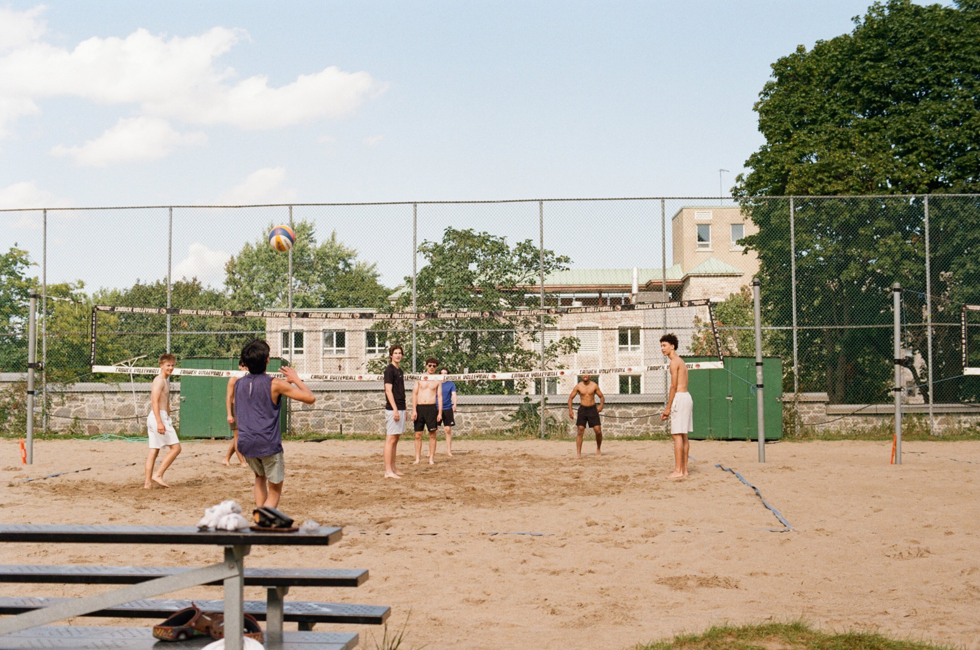 A group of men play volleyball at a park