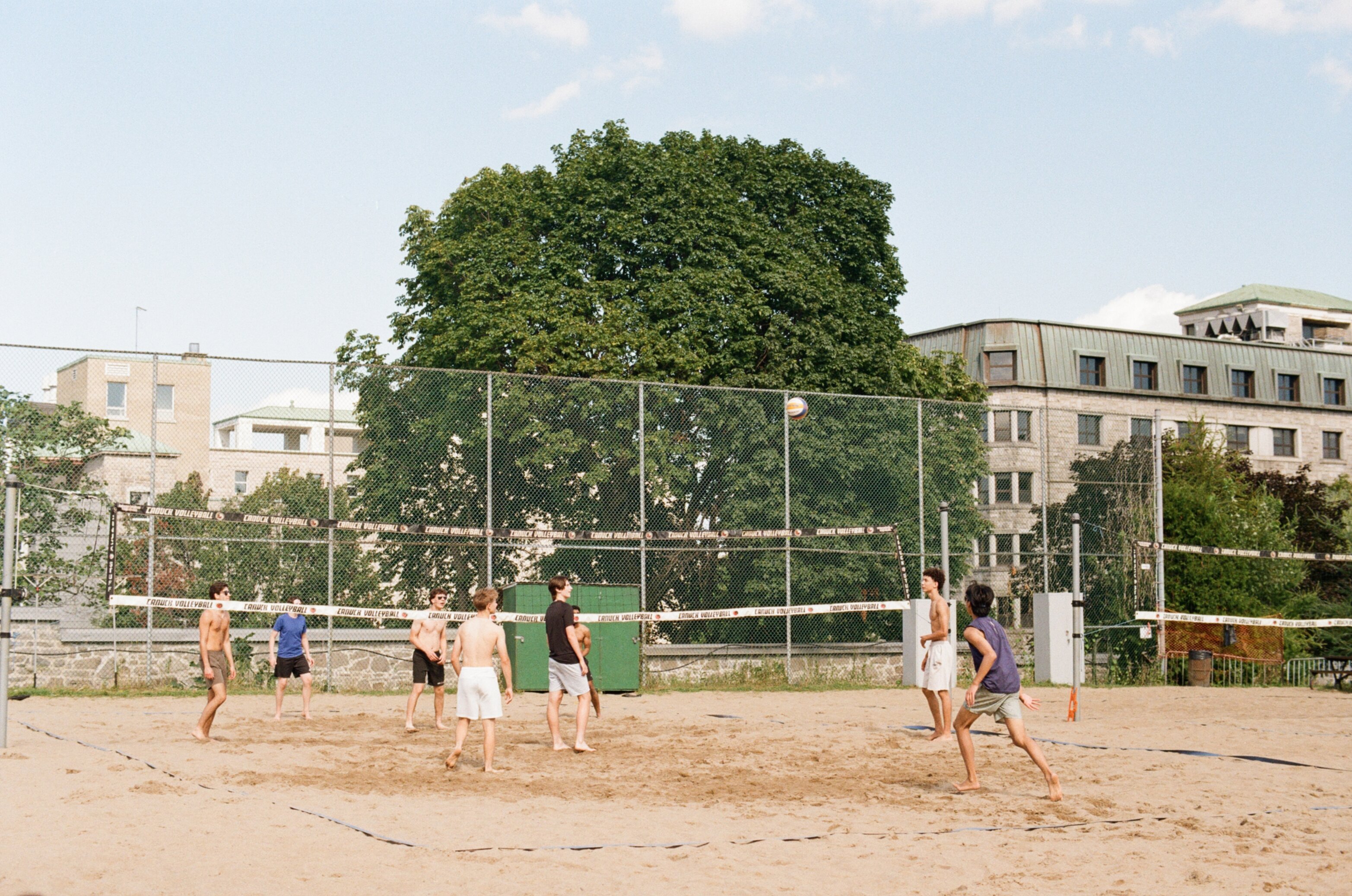 A group of men play volleyball at a park