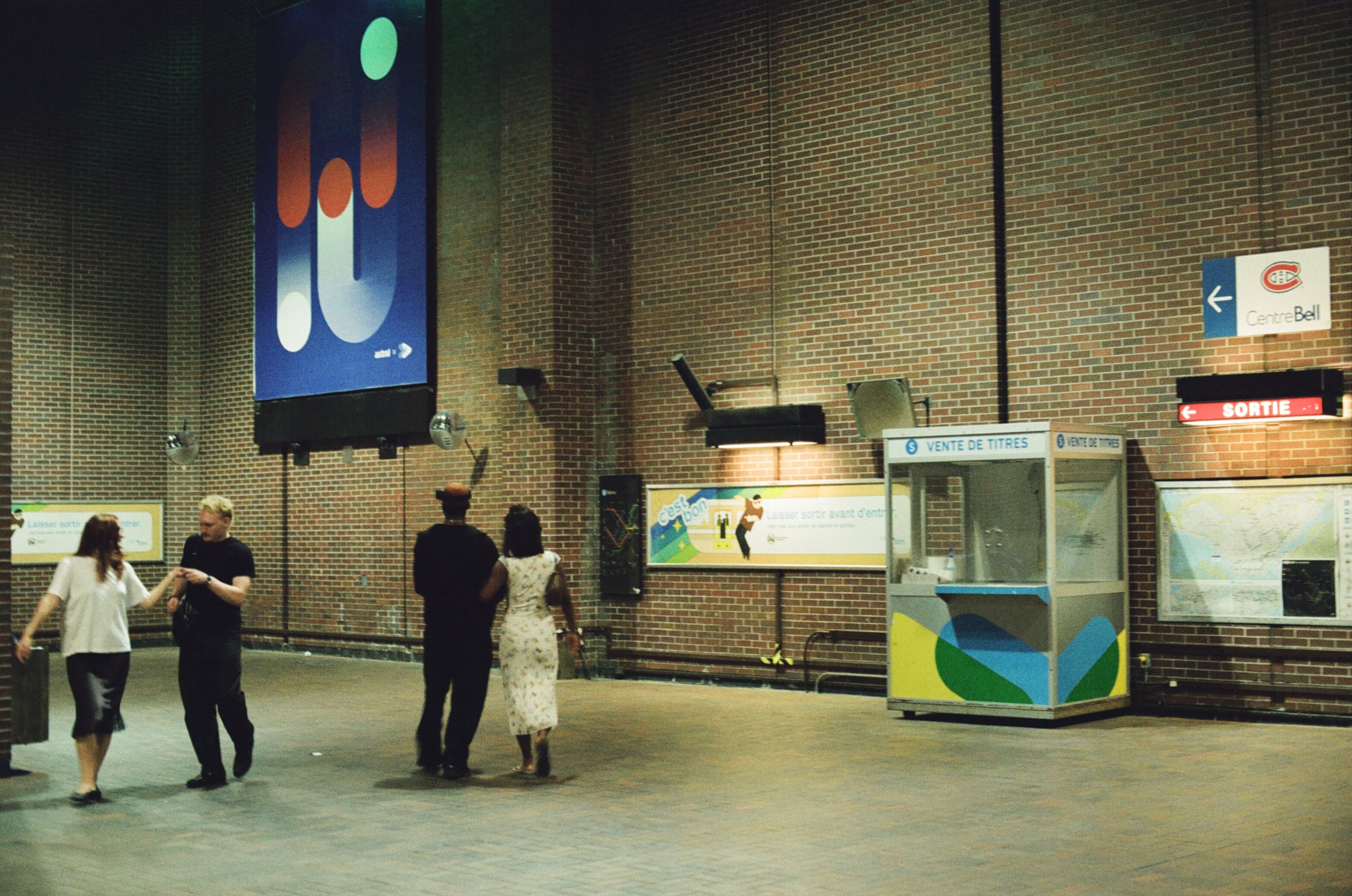 Subway passengers in an underground station with tall brick walls