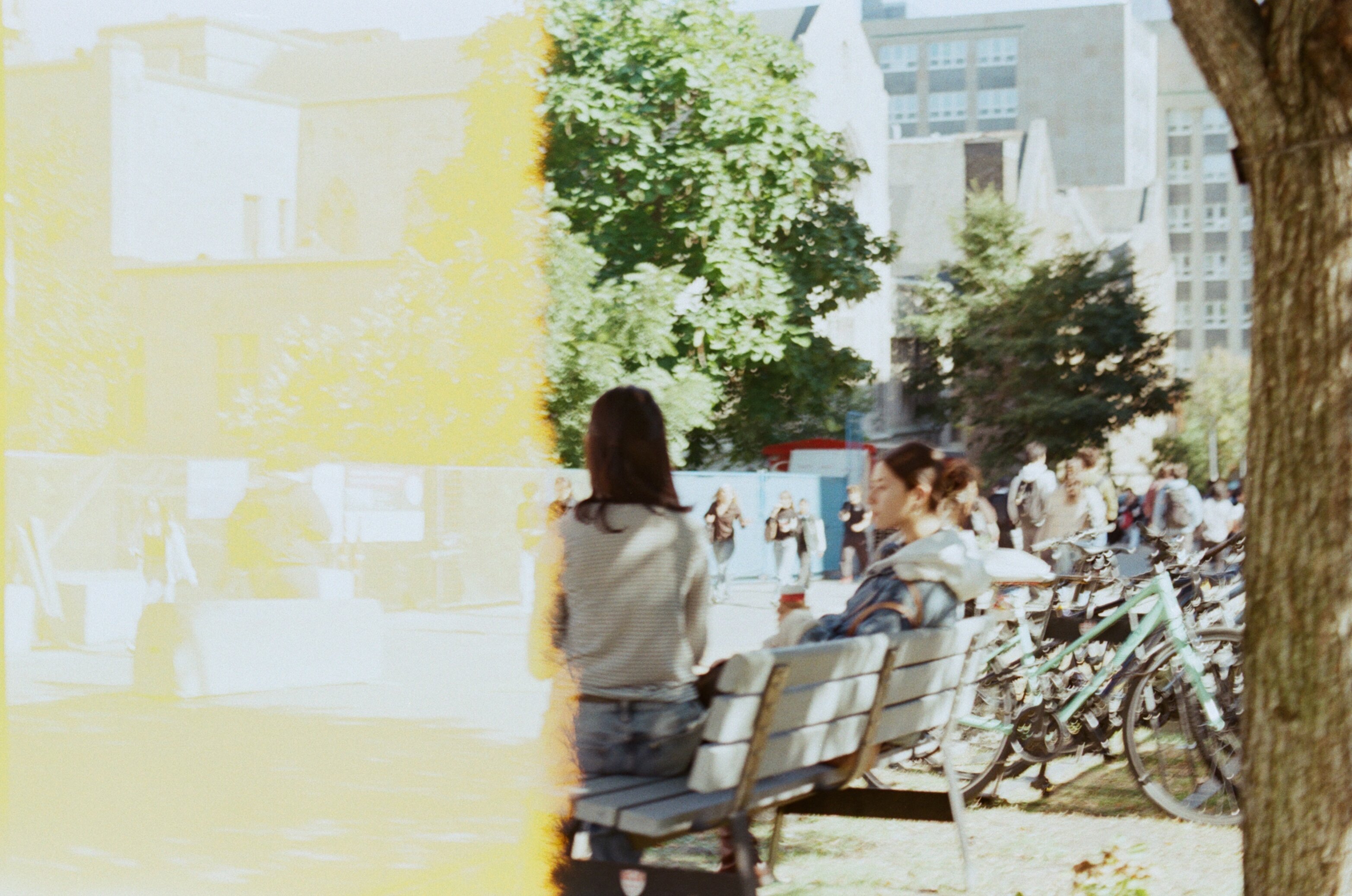 Two female students sitting on a bench on campus, with half the frame completely washed out