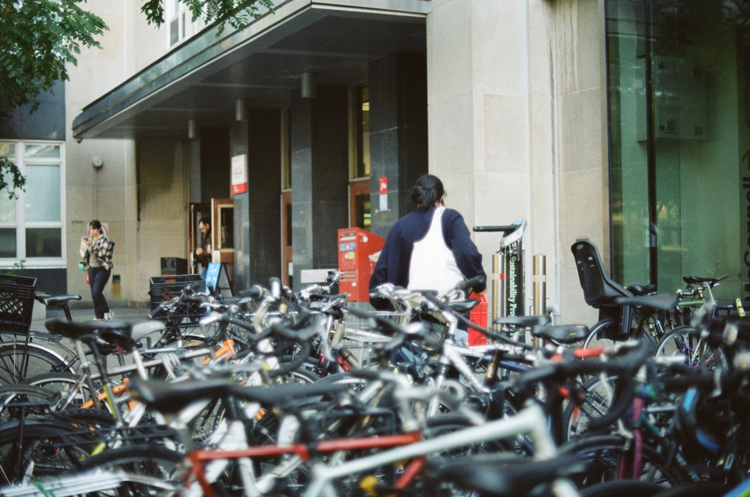 Female student unlocks her bicycle with many more bikes in the foreground