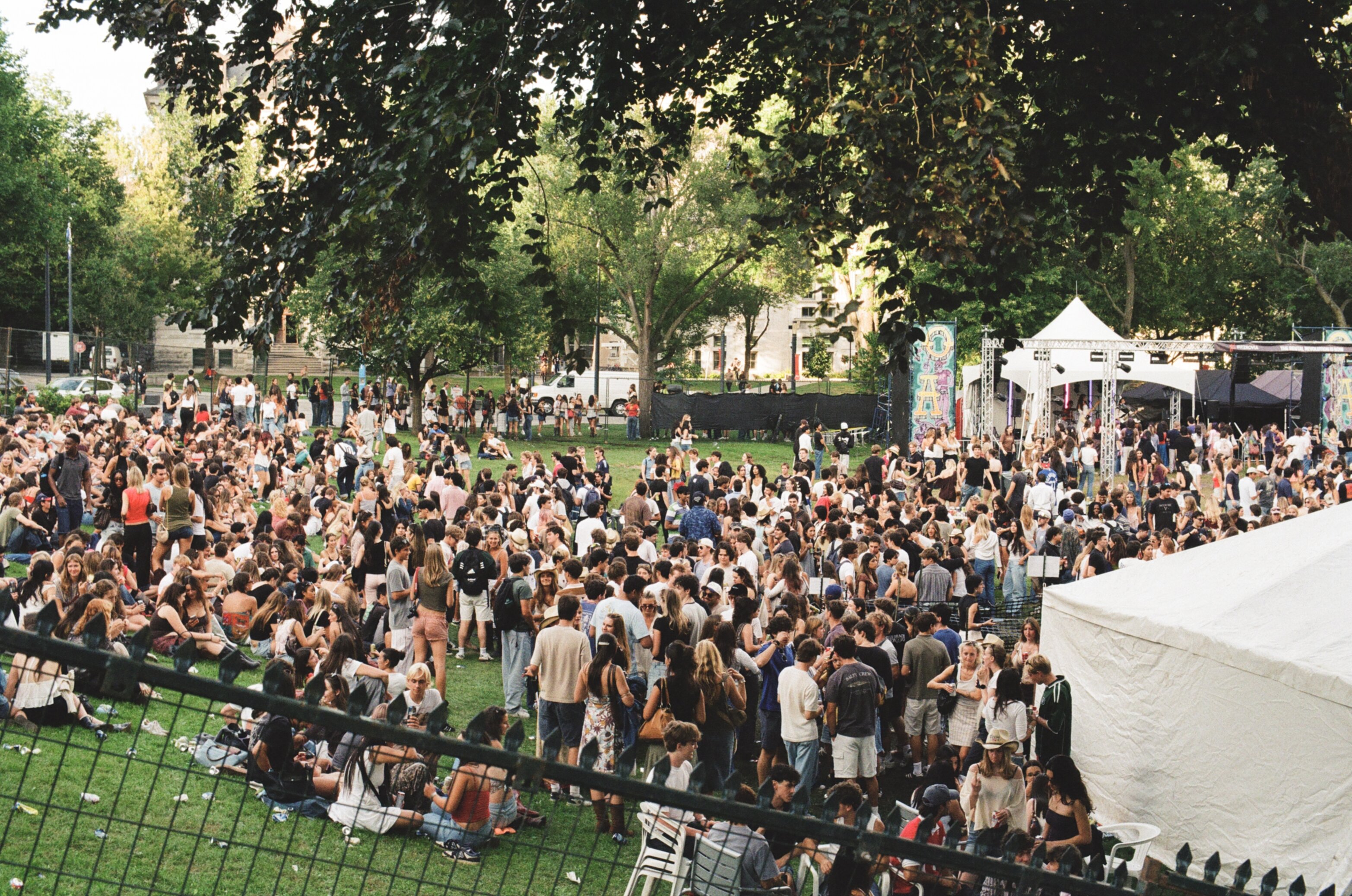 A crowd of students standing in a grass field at an outdoor concert