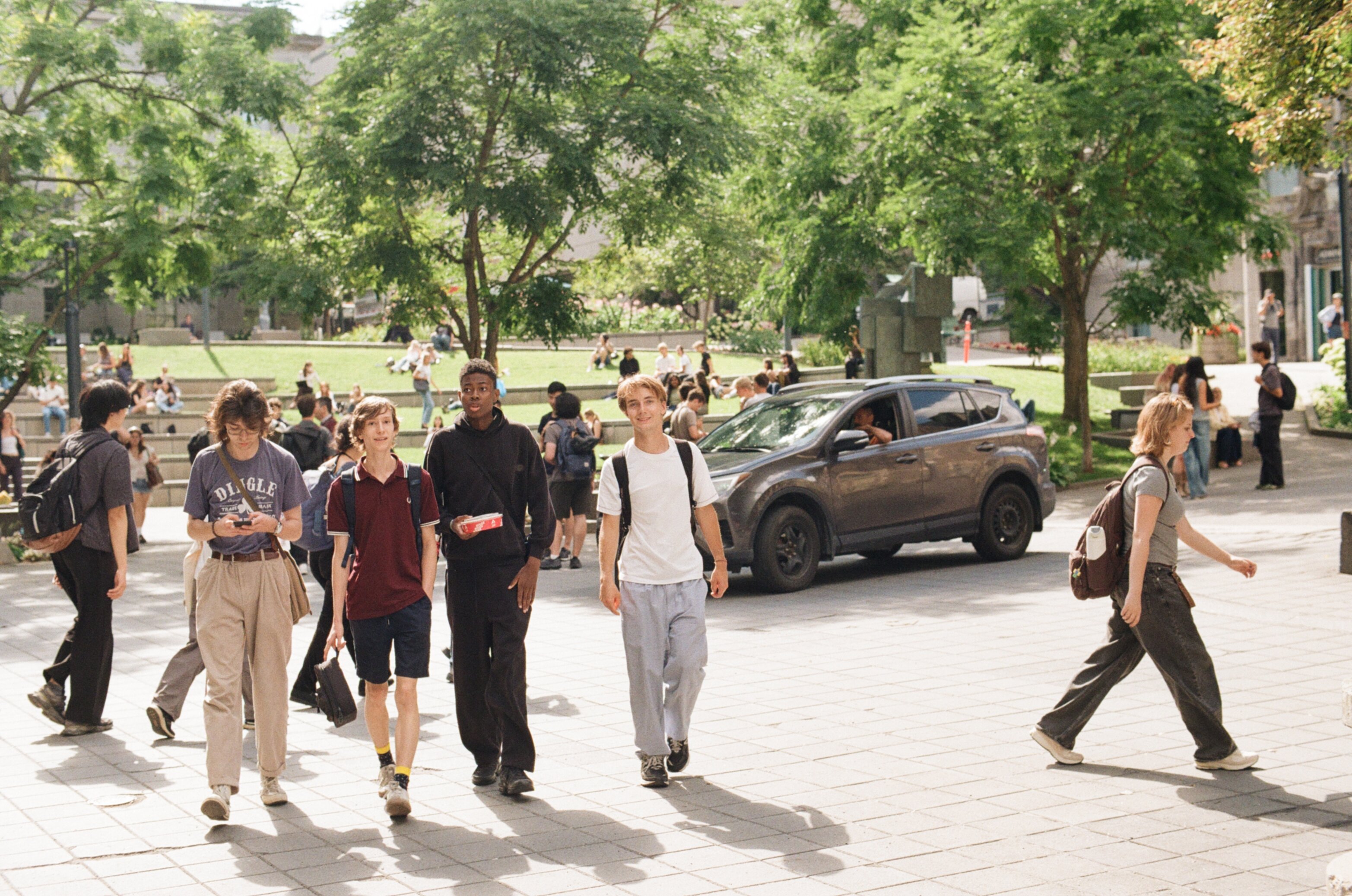 Group of four men walking across the pavement on campus