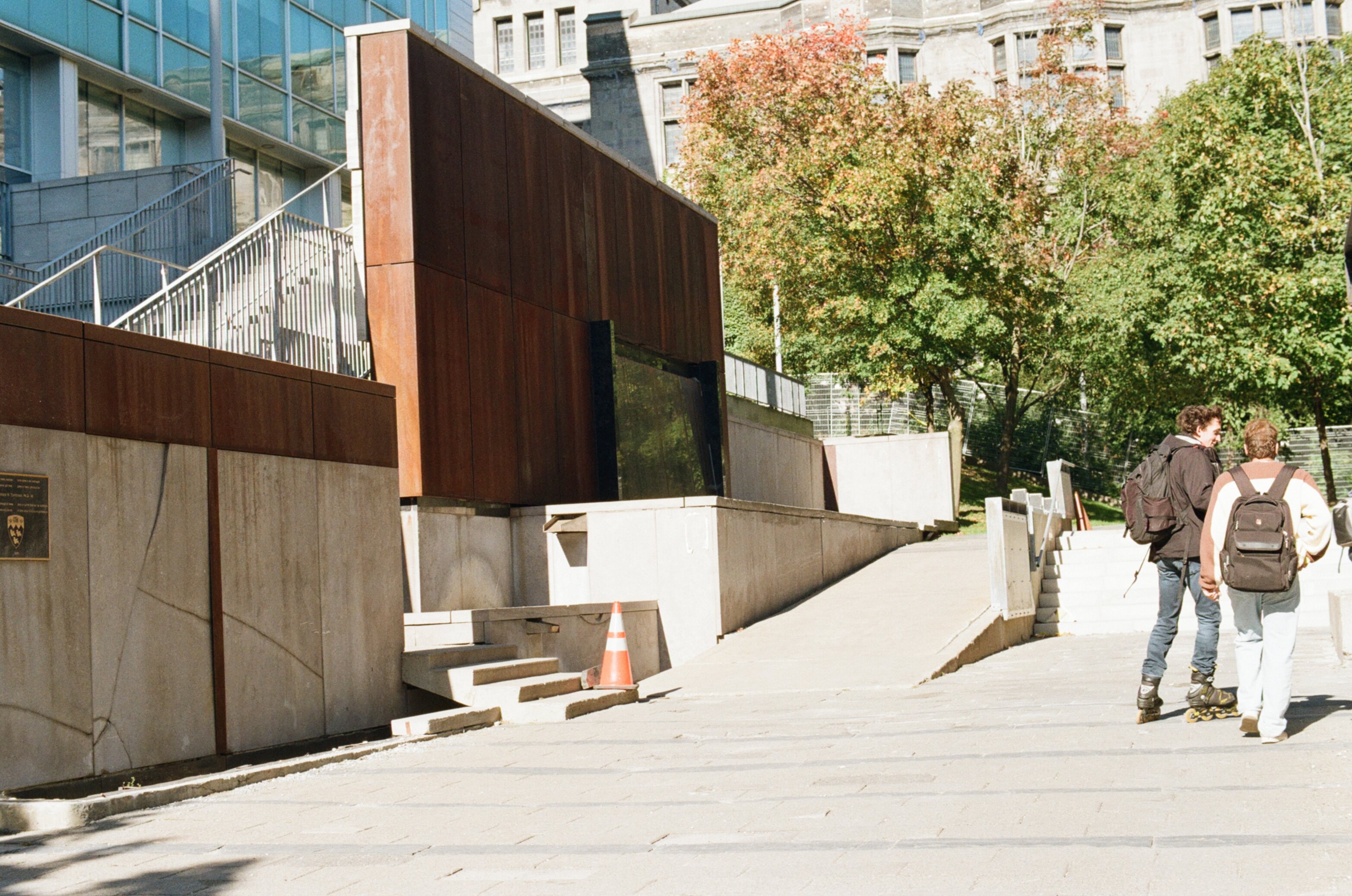 Students walk past a staircase plated with rusted metal in the morning